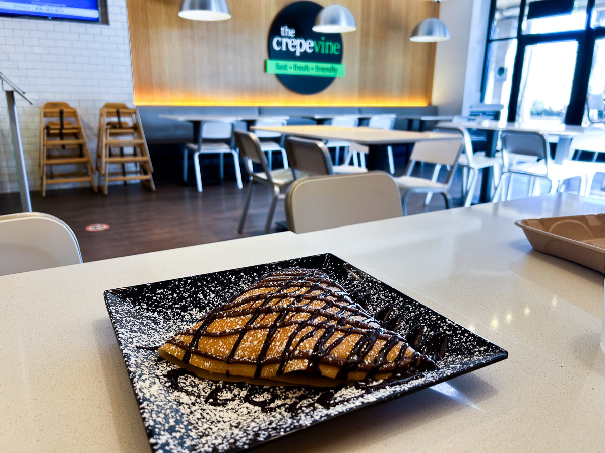 dessert crepe with chocolate drizzle on a table with black and green circle sign
